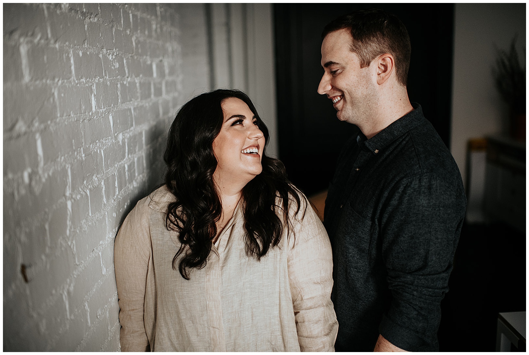 smiling couple in front of brick wall