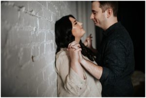 Couple holding hands in front of bring wall