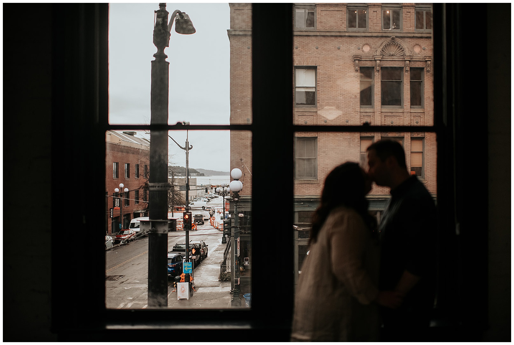 couple kissing in front of city window