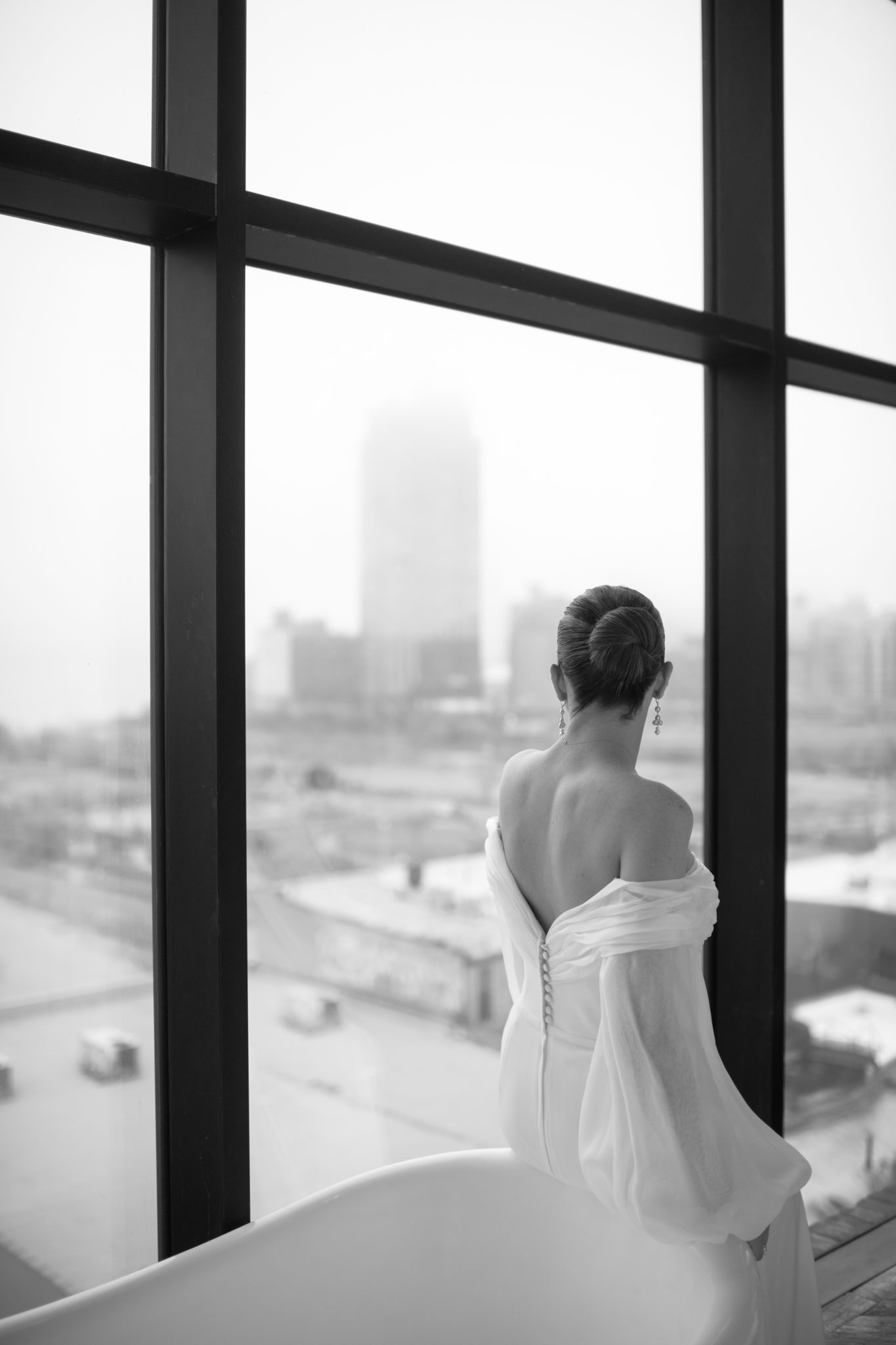 Black and white bridal portrait at a window overlooking the NYC skyline in Williamsburg, Brooklyn | New York wedding photographer Tonie Christine