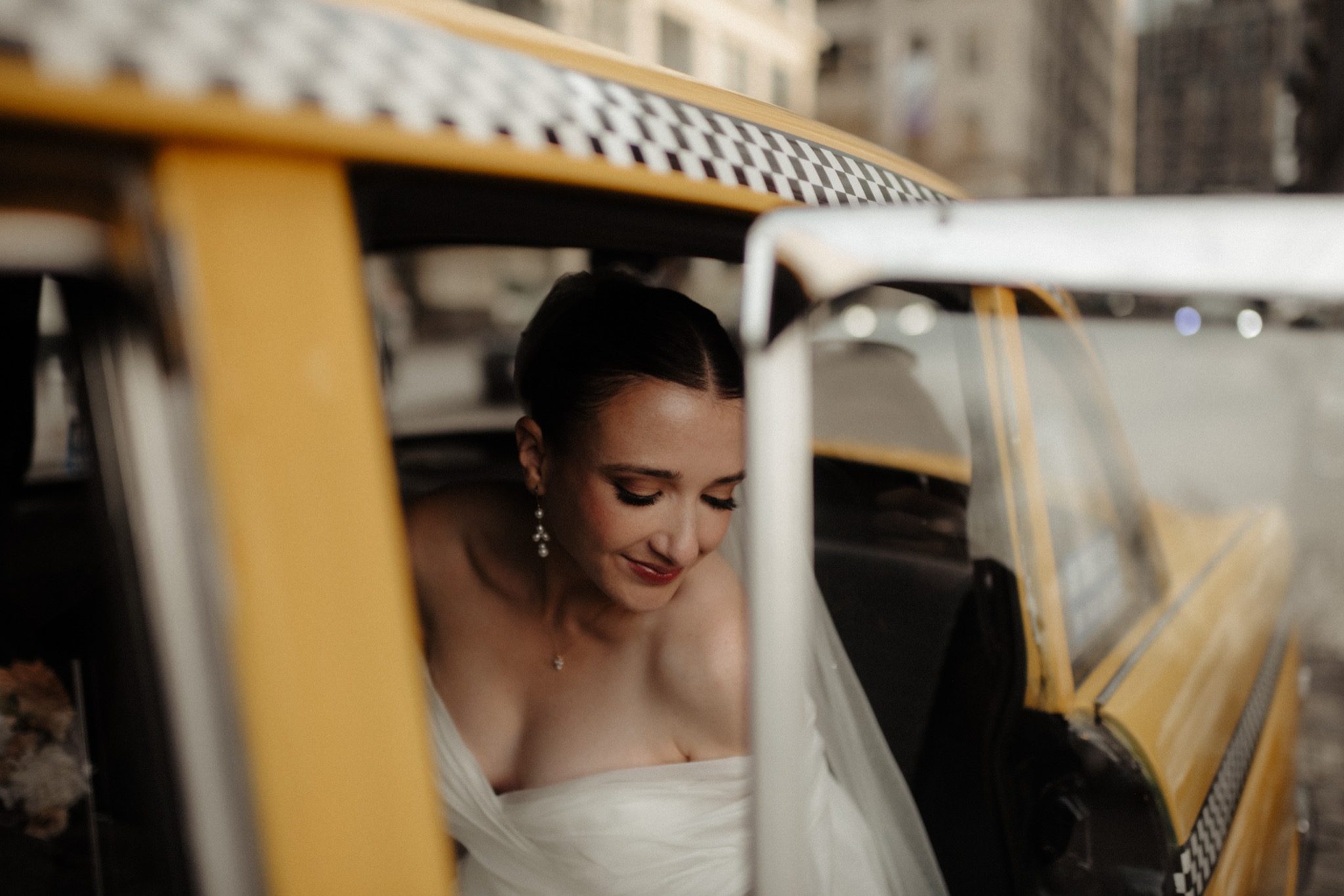 Bride smiling through the window of a vintage yellow cab in Brooklyn, NYC | New York wedding photographer Tonie Christine