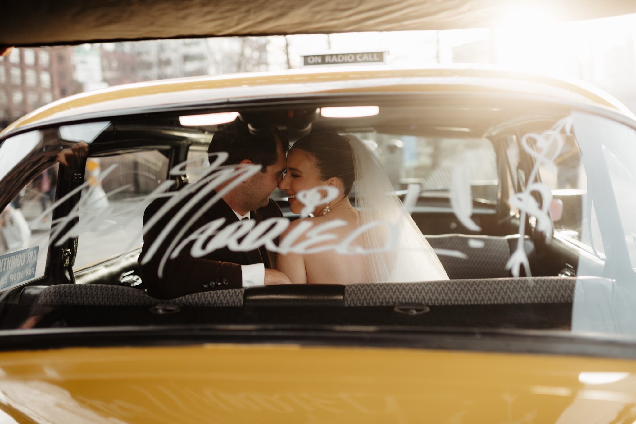 Bride and groom seen through the windshield of a vintage yellow cab in Brooklyn, NYC | New York wedding photographer Tonie Christine