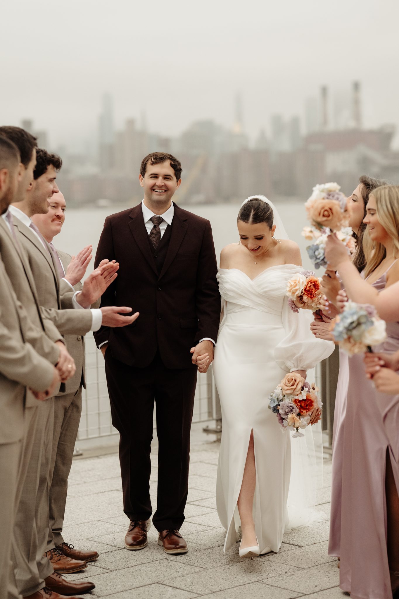 Wedding party celebrating on the Williamsburg waterfront with the NYC skyline behind them | New York wedding photographer Tonie Christine