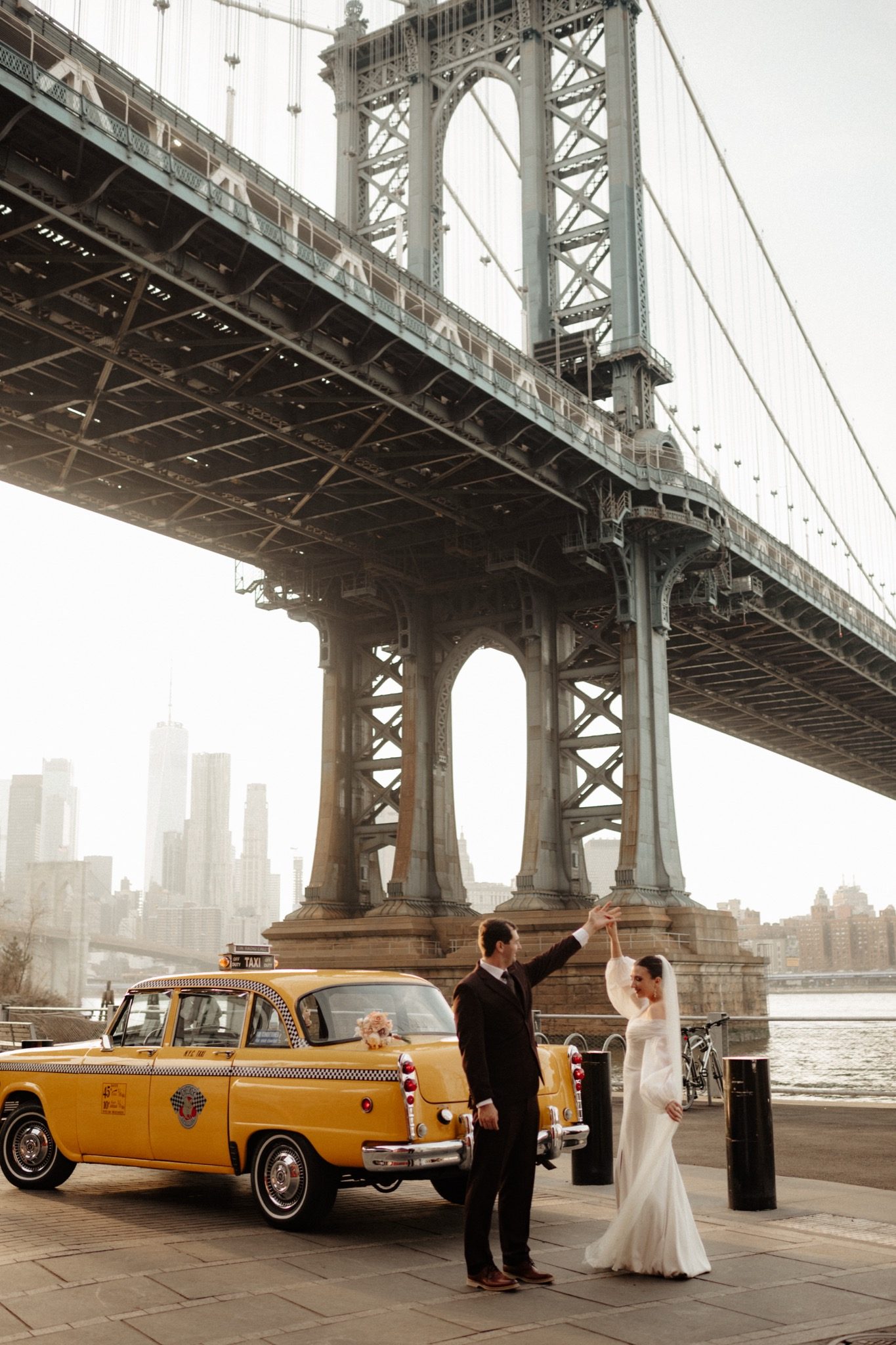 Bride and groom with a vintage yellow cab under the Manhattan Bridge in DUMBO, Brooklyn NYC | New York wedding photographer Tonie Christine